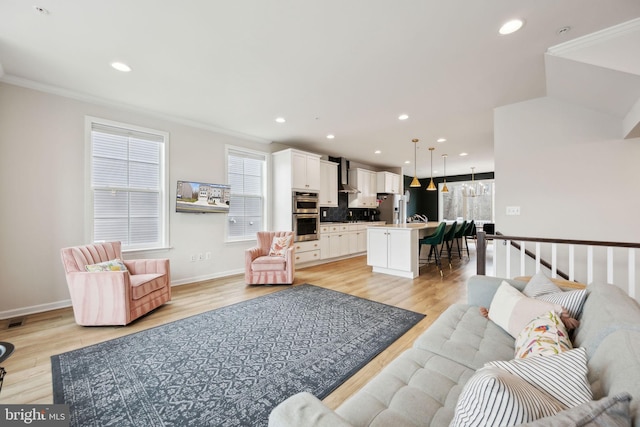 living area featuring light wood-style flooring, crown molding, and recessed lighting