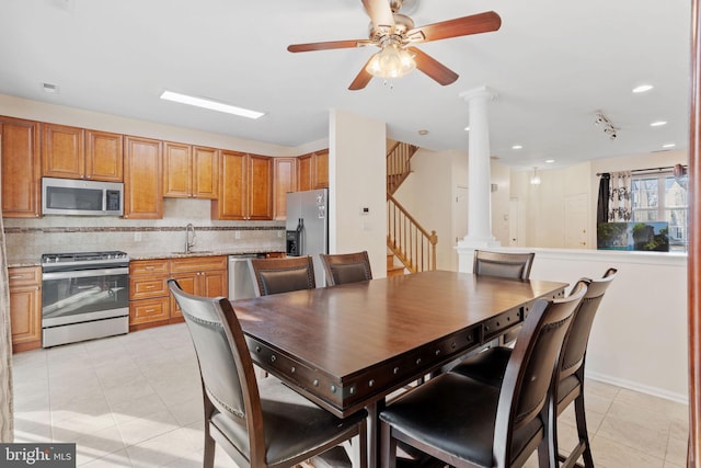 dining space featuring light tile patterned flooring, ceiling fan, stairway, and ornate columns