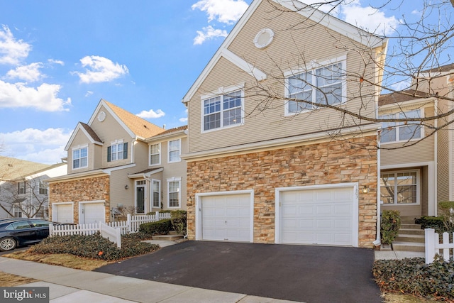 view of front of house with a garage, stone siding, and aphalt driveway