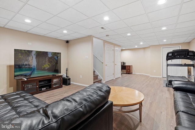 living area featuring recessed lighting, light wood-type flooring, a drop ceiling, baseboards, and stairs