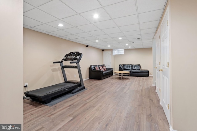 exercise room featuring a paneled ceiling, baseboards, wood finished floors, and recessed lighting