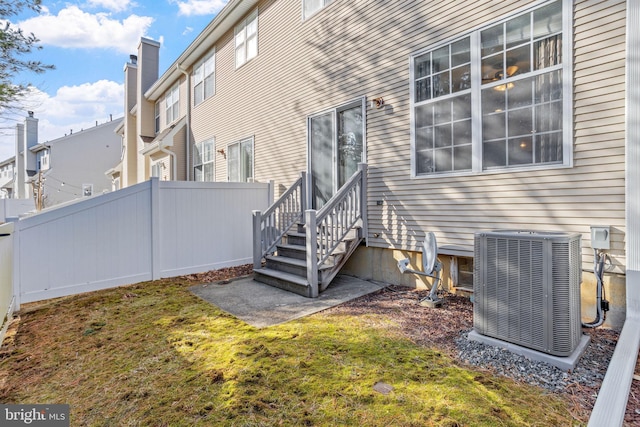 exterior space featuring entry steps, a lawn, a residential view, fence, and central air condition unit