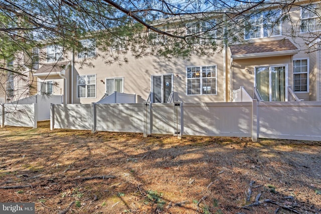 rear view of property featuring a shingled roof and fence