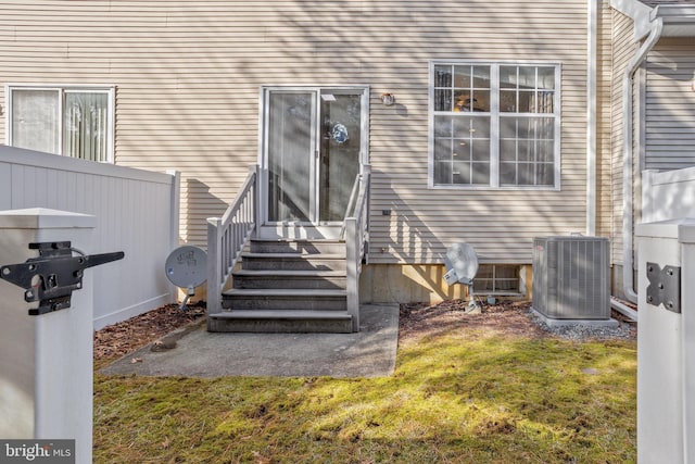 entrance to property featuring central AC, a lawn, and fence