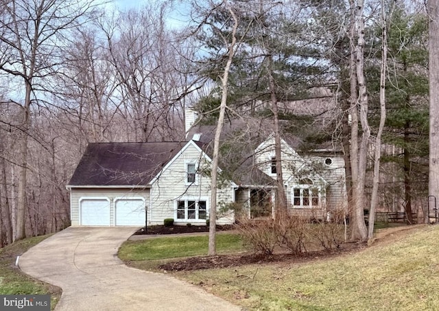 view of front of home featuring an attached garage, a chimney, concrete driveway, and a front yard