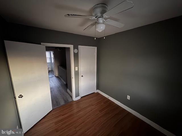 unfurnished bedroom with baseboards, dark wood finished floors, and a ceiling fan