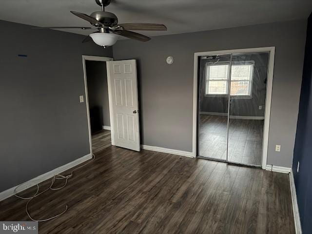 unfurnished bedroom with dark wood-style floors, ceiling fan, baseboards, and a closet