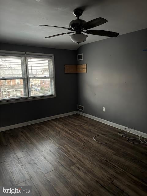 unfurnished room with dark wood-style flooring, visible vents, and baseboards