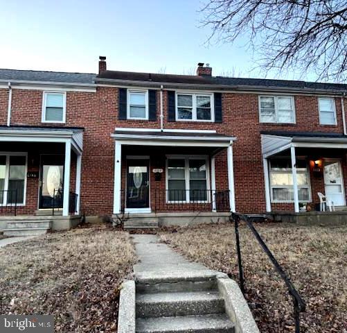 townhome / multi-family property featuring a porch, brick siding, and a chimney