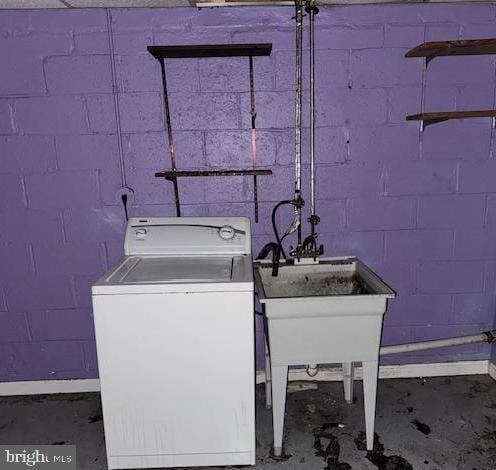 laundry area featuring concrete block wall and washer / dryer