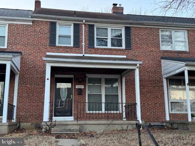 townhome / multi-family property with brick siding and a chimney