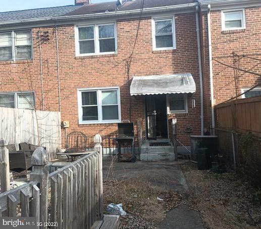 back of property featuring a chimney, fence, and brick siding