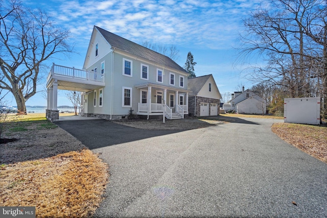 view of front facade with aphalt driveway, a porch, and roof with shingles