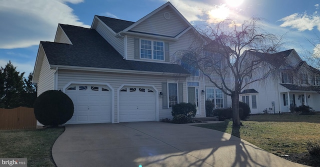 view of front of property featuring concrete driveway, roof with shingles, a front yard, and fence