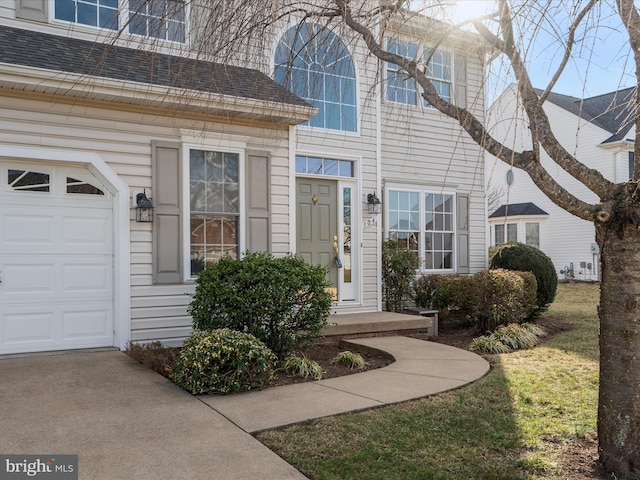 entrance to property featuring an attached garage and roof with shingles