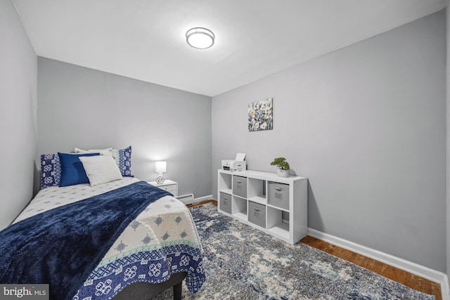 bedroom featuring baseboards, a baseboard heating unit, and wood finished floors