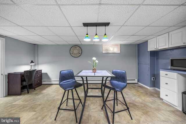 dining space with a drop ceiling and baseboard heating