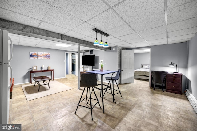 dining space featuring a paneled ceiling, baseboards, and a baseboard heating unit