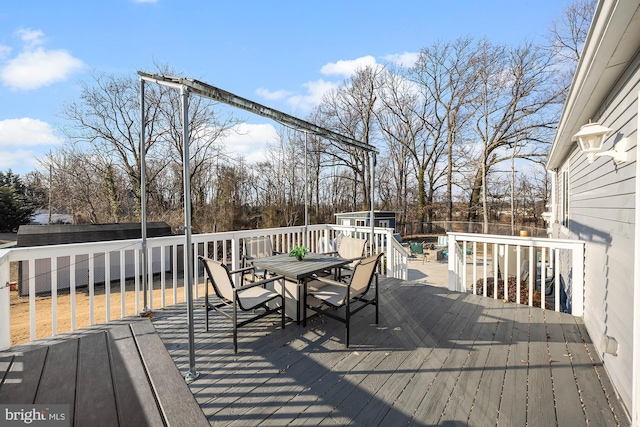 deck with a storage shed, a fenced backyard, an outbuilding, and outdoor dining space