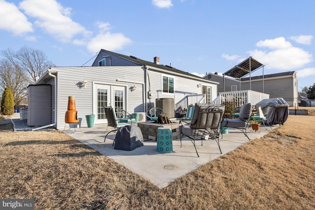 rear view of property featuring a patio, cooling unit, a fire pit, a yard, and french doors