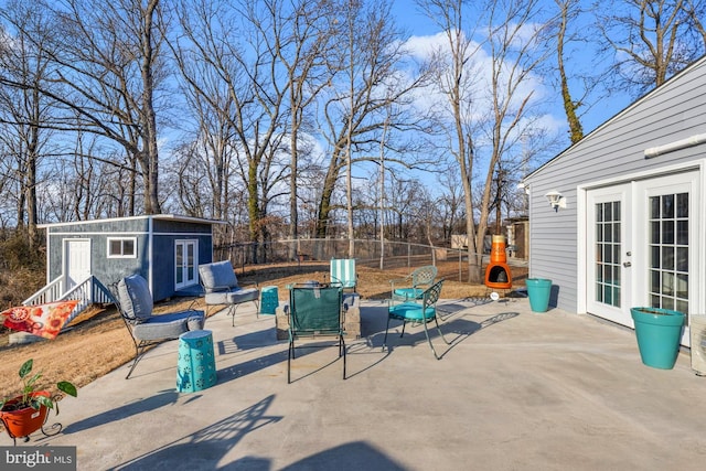 view of patio with fence, an outdoor structure, and french doors