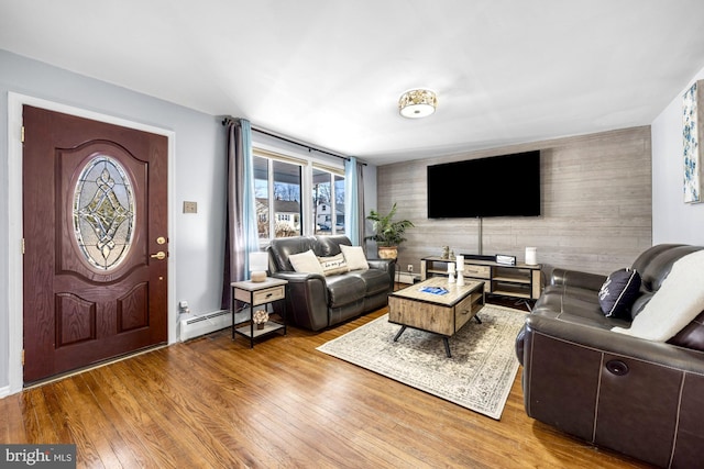 living area with a baseboard radiator, wood-type flooring, and an accent wall