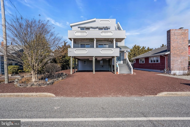 view of front of home with dirt driveway and a carport