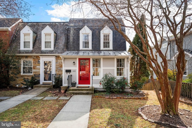 view of front of home featuring metal roof, stone siding, a standing seam roof, and fence