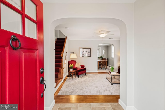 entryway with arched walkways, stairway, and baseboards