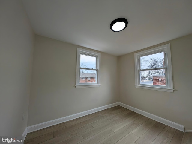 spare room with plenty of natural light, baseboards, and wood finished floors