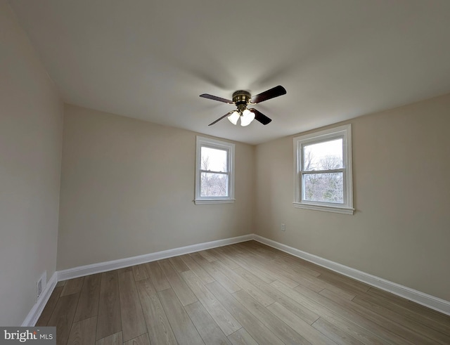 spare room featuring a ceiling fan, wood finished floors, visible vents, and baseboards