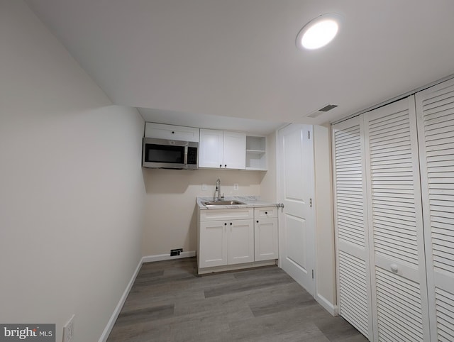 laundry room with light wood-style floors, visible vents, a sink, and baseboards