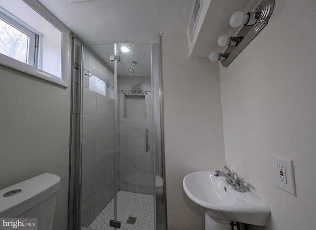 full bath featuring toilet, a stall shower, visible vents, and a sink