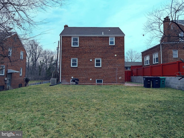 back of property featuring brick siding, a lawn, central AC unit, and fence