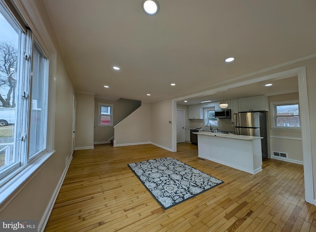 kitchen with baseboards, visible vents, stainless steel appliances, light countertops, and light wood-style floors