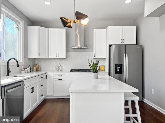 kitchen featuring decorative backsplash, a kitchen island, appliances with stainless steel finishes, white cabinetry, and a sink