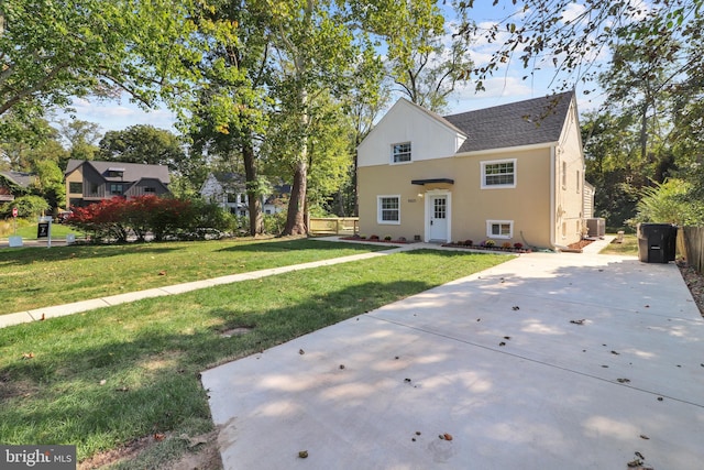 view of front of home featuring a shingled roof, central air condition unit, a front yard, and stucco siding