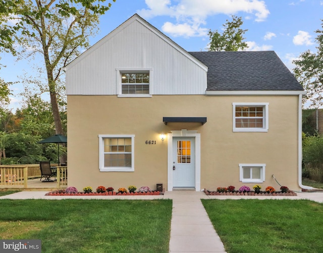 view of front of home featuring a front lawn, roof with shingles, and a patio area