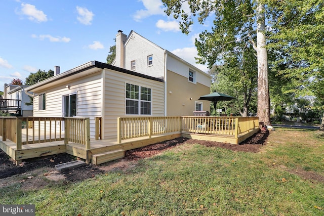 back of house featuring a deck, a lawn, and a chimney