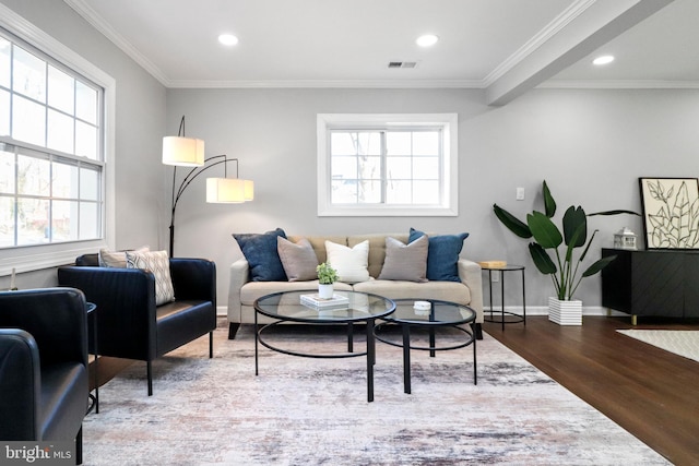 living area with ornamental molding, visible vents, plenty of natural light, and wood finished floors