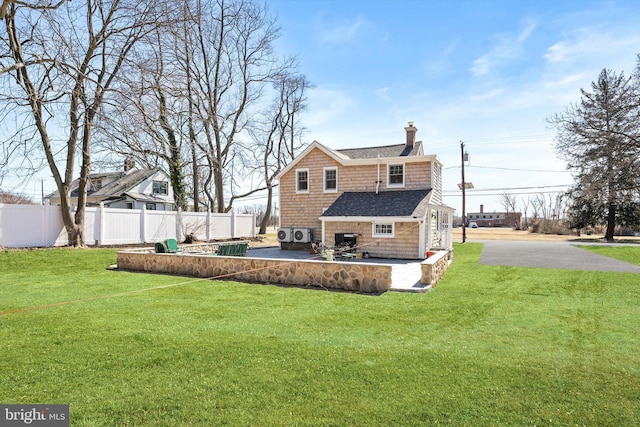 rear view of property featuring a lawn, a chimney, and fence