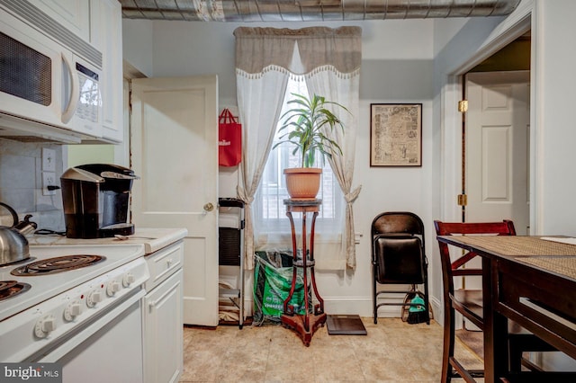 kitchen featuring white appliances, baseboards, white cabinets, light countertops, and tasteful backsplash