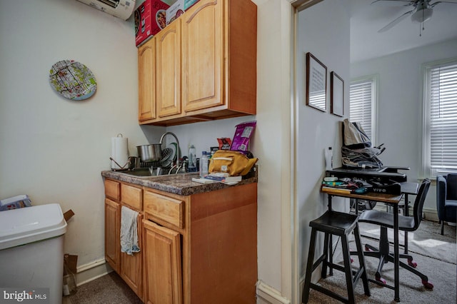 kitchen with dark countertops, a sink, ceiling fan, a wall mounted air conditioner, and baseboards