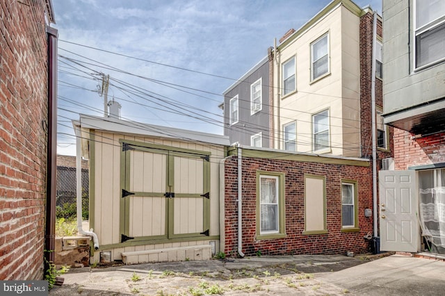 exterior space with a storage unit, an outdoor structure, and brick siding