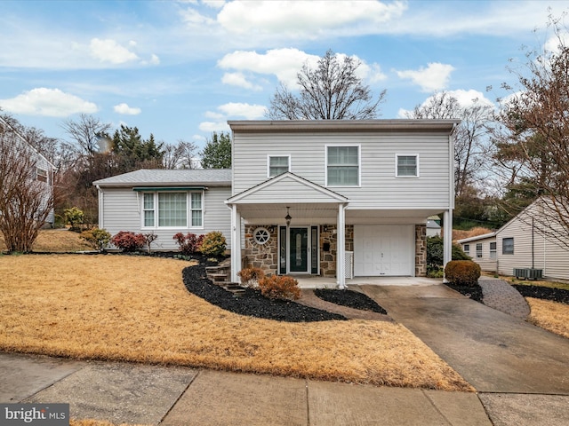 traditional home with an attached garage, stone siding, cooling unit, and concrete driveway