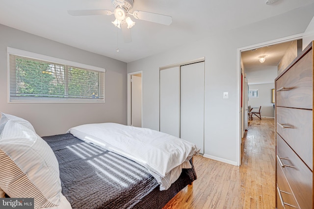 bedroom featuring a ceiling fan, light wood-style flooring, baseboards, and a closet