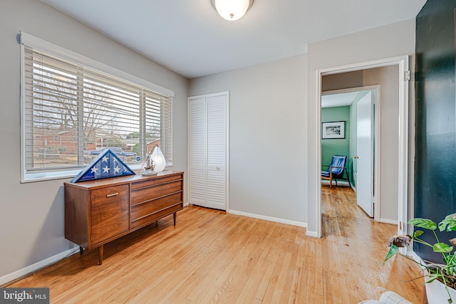 bedroom with light wood finished floors, baseboards, and a closet