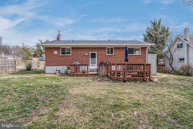 back of property with brick siding, a lawn, a wooden deck, and fence