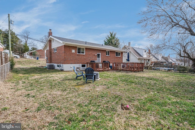 back of house featuring a wooden deck, a chimney, fence, a yard, and brick siding