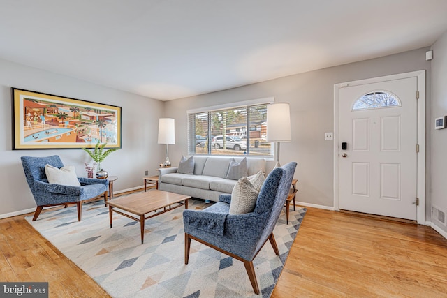 living area featuring visible vents, light wood-style flooring, and baseboards